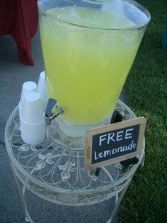 a lemonade dispenser sitting on top of a table with a free sign next to it