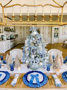 a dining room table decorated for christmas with blue and white decorations