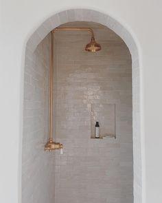 a bathroom with a shower, toilet and bathtub in it's corner next to a brick wall