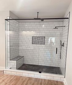 a bathroom with white tile and wood flooring on the walls, along with a walk in shower