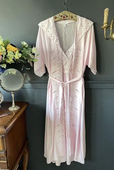 This unique set, designed in the 1970s, features a silk robe and nightgown that beautifully combine nostalgia and elegance, with floral embroidery adorning the necklines. Crafted from pure Rose silk, this magnificent set offers a luxurious and comfortable experience. The robe is adorned with delicate embroidery on the neckline, cuff edges, and pocket edges, while the nightgown's neckline reflects the same elegance with matching embroidery. Please check your measurements below. Size: Small Robe: V-neck Lace Trim Robe For Daywear, V-neck Robe With Lace Trim For Daywear, Feminine V-neck Robe For Daywear, Lace Trim V-neck Robe For Daywear, Vintage V-neck Wedding Sleepwear, Vintage Pink Robe For Spring, Vintage Summer Sleepwear, Pink Feminine Robe, Feminine Pink Robe For Daywear