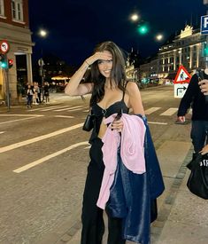 a woman is walking down the street at night