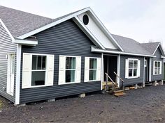 a row of houses sitting next to each other on top of a dirt field with trees in the background