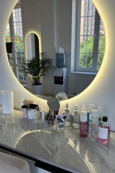 a bathroom counter topped with lots of personal care items and a round mirror above it