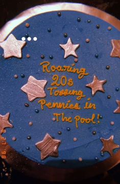 a blue cake with gold stars and writing on the side that says roaring 205 young pennies in the pool