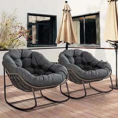 two chairs sitting on top of a wooden floor next to an umbrella covered patio area