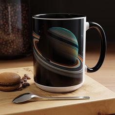 a coffee mug sitting on top of a wooden table next to a spoon and cookie