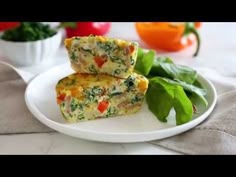 two pieces of quiche on a plate with spinach and tomatoes in the background