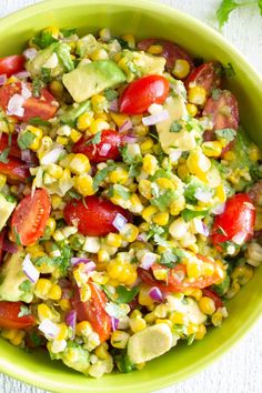 a green bowl filled with corn, tomatoes, avocado and cilantro