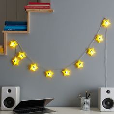 a laptop computer sitting on top of a desk next to yellow star shaped string lights