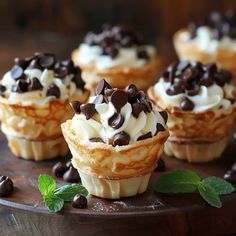 mini desserts with chocolate chips and whipped cream on top are sitting on a wooden platter