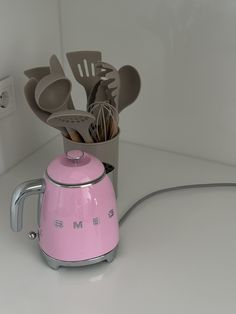 a pink toaster with spoons and utensils sticking out of the top