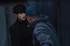 a man standing next to a woman in a room with dark hair and black clothes