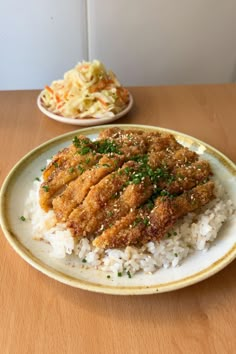 a plate with rice and meat on it next to another plate filled with coleslaw