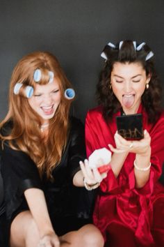 two women sitting next to each other with their mouths open and one holding a cell phone