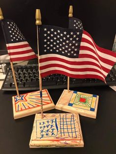 three small american flags sitting on top of a desk next to a keyboard and mouse