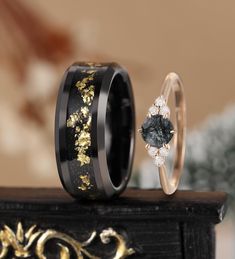 two wedding bands with black and gold flowers on them, one has a diamond in the center