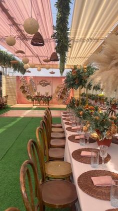 a long table is set with place settings and flowers on it for an outdoor function