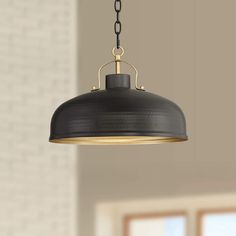 a black and gold pendant light hanging from a ceiling in a room with brick walls