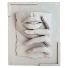 a white sculpture with two hands covering it's face