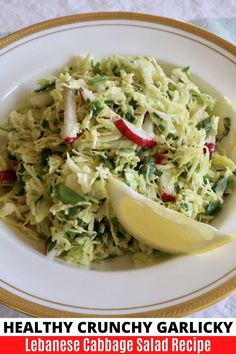 a white plate topped with cabbage salad and lemon wedges