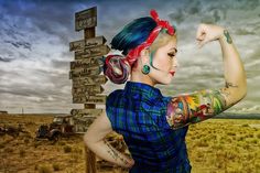 a painting of a woman with tattoos pointing at a sign in the middle of an open field