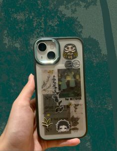 a person holding up a cell phone case with stickers on it