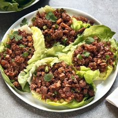 lettuce wraps with ground meat and garnishes on a white plate