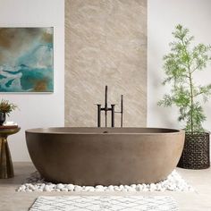 a bath tub sitting on top of a white floor next to a painting and potted plant