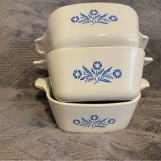 three white dishes with blue flowers are stacked on top of each other and one is empty