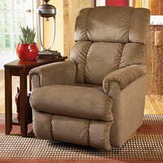 a brown recliner sitting on top of a rug next to a wooden end table