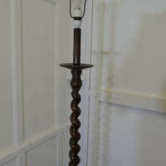 an old fashioned lamp with a candle on it's base in a room that has white walls