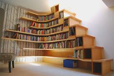 there are many bookshelves in the room and one has a chair next to it