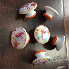 four decorative knobs with flamingos painted on them sitting on a table next to each other