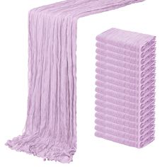 a pile of purple towels sitting on top of a white floor next to a pink towel