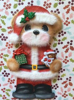 a teddy bear wearing a santa suit and holding a christmas ornament