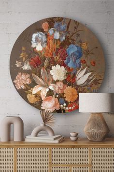 a vase filled with lots of flowers on top of a wooden table next to a lamp