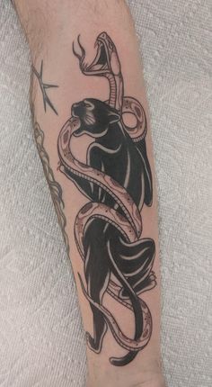 a black and white tattoo on the leg of a man with a snake wrapped around his arm