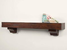 a wooden shelf with some books and vases on top of it next to a white wall