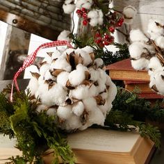 cotton balls and greenery are on top of an open book in front of a christmas wreath