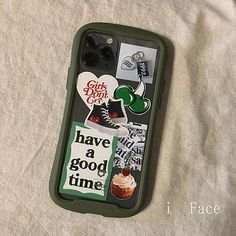 an iphone case with stickers on it sitting on top of a white sheet covered bed