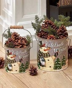 two metal buckets filled with pine cones on top of a wooden floor