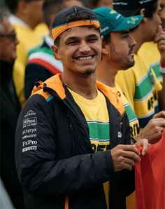 a group of men standing next to each other holding an orange and green flag in their hands