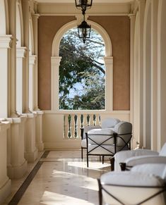 two white chairs sitting on top of a stone floor next to an open window with arched windows