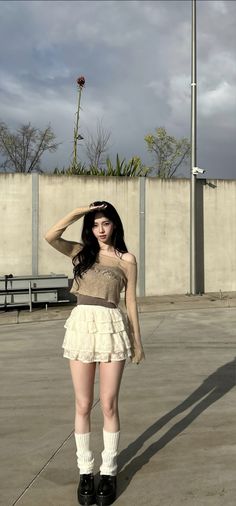 a woman in short skirt and boots posing for the camera with her hand on her head