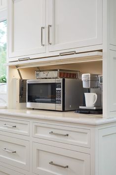 a microwave oven sitting on top of a kitchen counter next to a coffee pot and cup