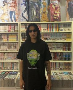 a man standing in front of a book shelf filled with comic books and anime memorabilia