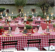 a red and white checkered table cloth covered outdoor dining area with lit candles on the tables