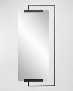 an empty mirror hanging on the wall with a black frame and metal bar around it