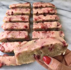 a person holding up a piece of cake with pink icing on top of it